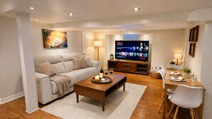 Un salon comprenant un canapé, une table basse, un téléviseur et un coin repas avec des chaises et une table.