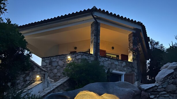 A stone house with a covered patio and a rock formation in front. - Villa 'Vista Mare Cala Ginepro' with Sea View, Private Terrace and Air Conditioning (Punta Molara)
