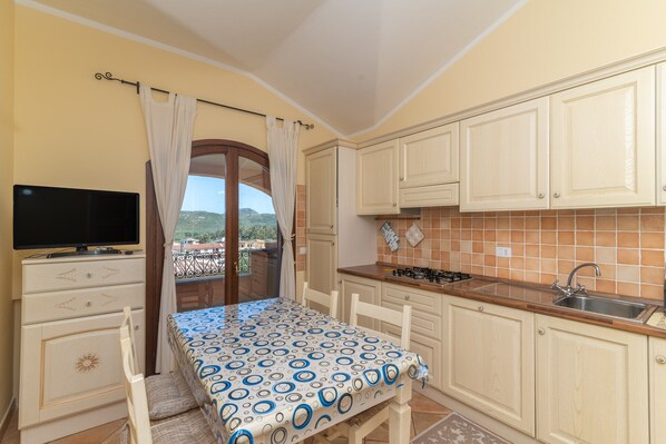 Cocina compacta con una mesa de comedor, un televisor y vistas al exterior.