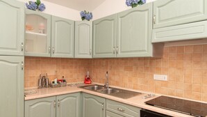 Une cuisine avec des meubles de couleur vert clair, une cuisinière noire et un évier.