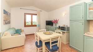 Un espace de vie compact comprenant une table à manger, des chaises, un canapé, un téléviseur et un coin cuisine.