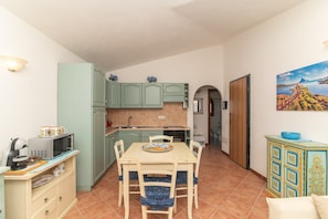 A compact kitchen with a dining table, chairs, and a microwave.