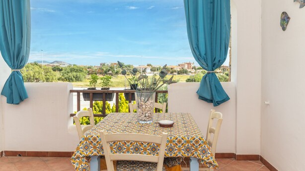 Un balcon avec une table, des chaises et une vue sur la verdure et les bâtiments.