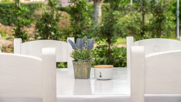 Ein weißer Tisch mit einem Topf Lavendel und einer weißen Tasse mit Deckel.