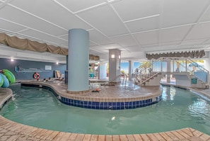 An indoor swimming pool with a tiled edge, a central column, and a staircase leading to a higher level.