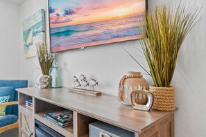 A living room with a wooden TV stand, decorative fish figurines, and a vase with tall grasses.
