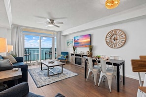A spacious living room with a balcony, a dining area, and a kitchen.