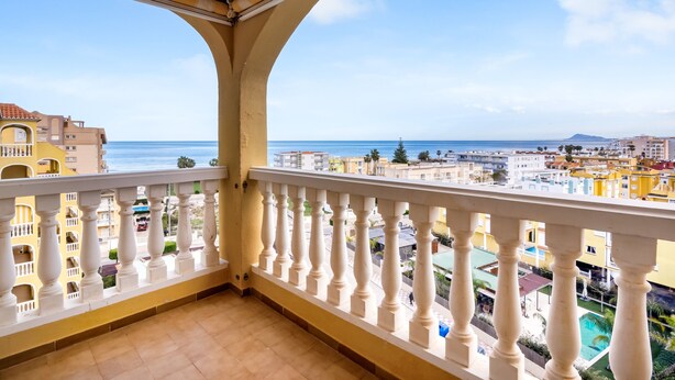A balcony with a view of the sea and buildings.