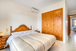 Una camera da letto con un letto in legno, un comodino, un armadio e un condizionatore d'aria.