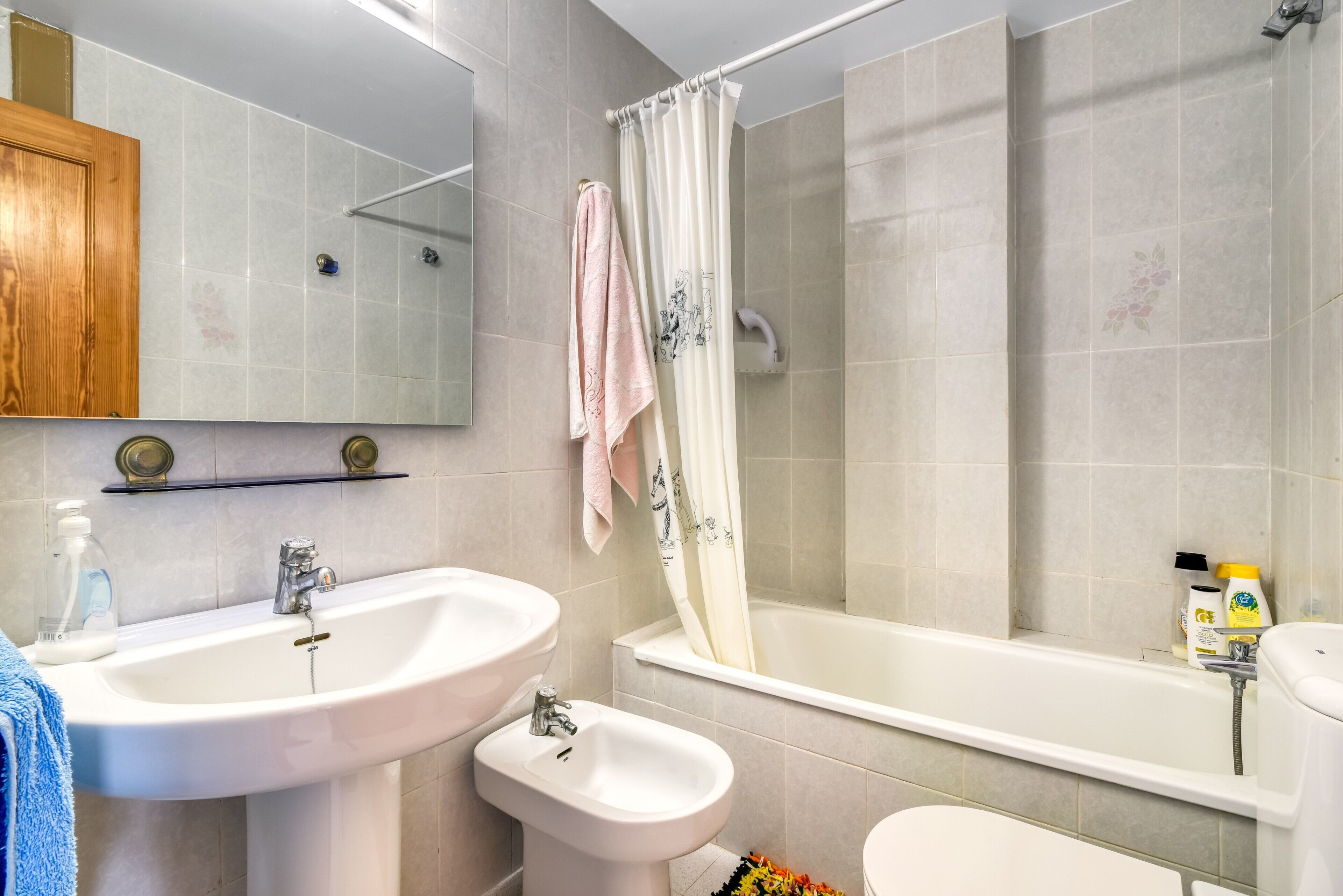 A bathroom with a sink, bidet, and bathtub.