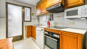 A kitchen with wooden cabinets, a dishwasher, an oven, and a microwave.