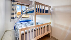 A bunk bed room with a window, curtains, and a view of the outside.