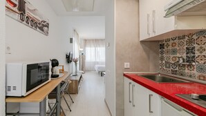 Cocina compacta con microondas, lavamanos y encimera roja.