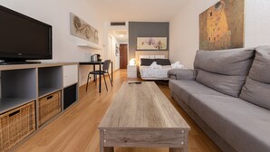 A modern living room with a flat-screen TV, a sofa, a coffee table, and a painting on the wall. - Apartment 'Chick' with Wi-Fi and Air Conditioning (Sevilla)