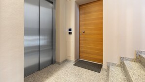 En gang med elevator i metal og en dør i træ.