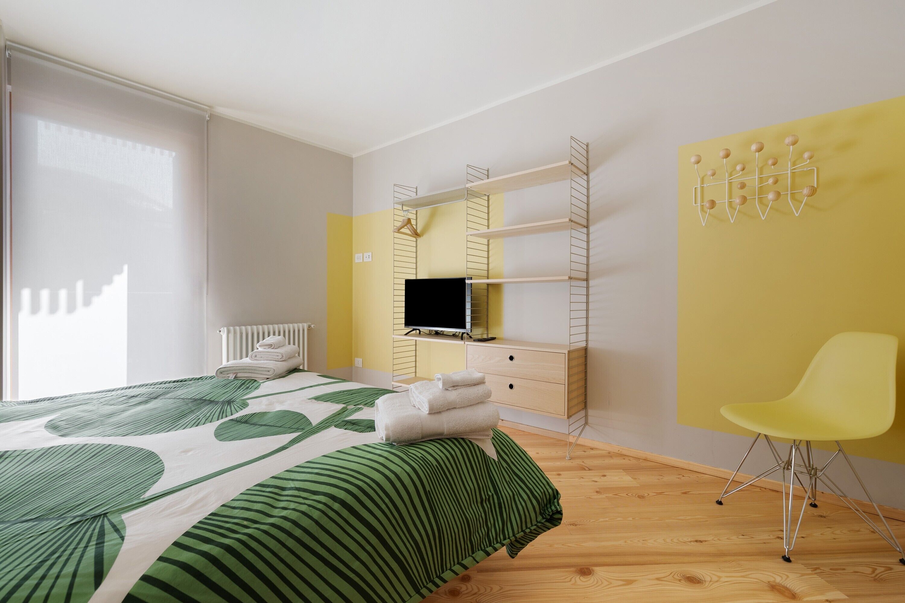 Ein Schlafzimmer mit einem Bett, einem Fernseher, einem Sessel und einem Regal.