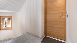 A hallway with a wooden door, a window with a view, and a carpeted floor.