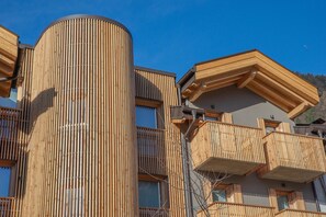 A modern building with a cylindrical structure and wooden balconies. - Apartment 'Yellow' with Mountain View, Balcony and Wi-Fi (Carisolo)