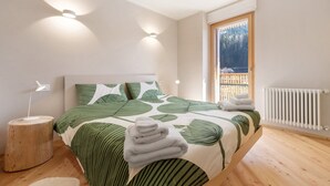 A bedroom with a bed, bedside lamps, a radiator, and a window with a view.