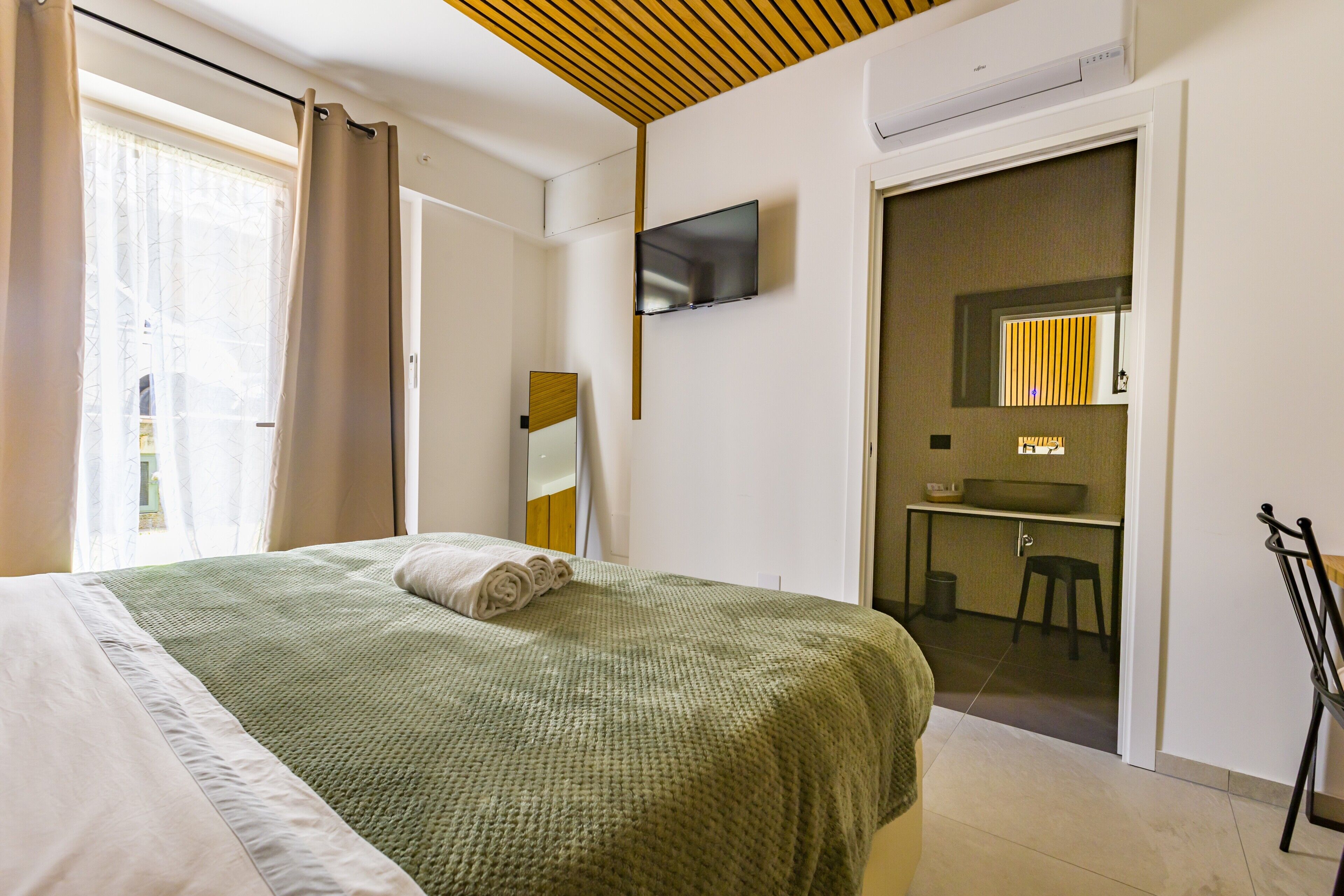 Een hotelkamer met een bed, een televisie, een bureau en een badkamer.