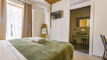 Een hotelkamer met een bed, een televisie, een bureau en een badkamer.
