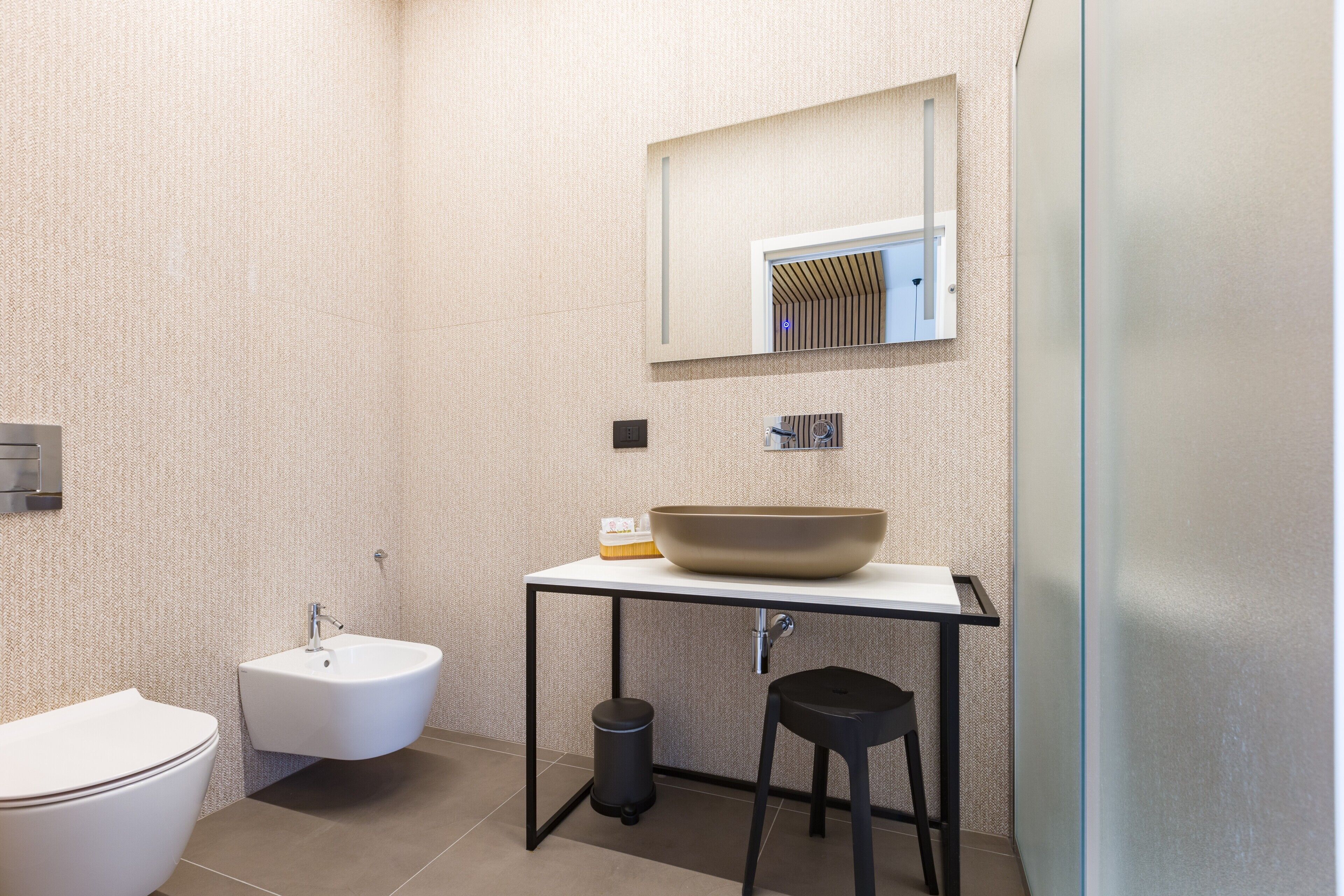 Een moderne badkamer met een wit wastafel, toilet en bidet.