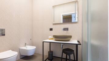 Een moderne badkamer met een wit wastafel, toilet en bidet.