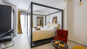 Ein modernes Hotelzimmer mit einem Himmelbett, einem roten Sessel, einem kleinen Tisch mit einer Pflanze und einem großen Spiegel.