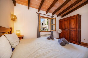 A bedroom with a bed, a wooden wardrobe, a window, and a wall-mounted fan.