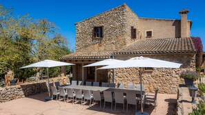 Un edificio de piedra con patio, mesas al aire libre y sombrillas.