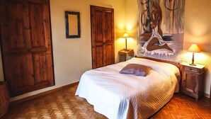 A bedroom with a large bed, wooden floors, two wooden doors, a painting on the wall, and two bedside lamps. - Courthézon near Avignon, holiday villa, swimming pool, beautiful park. (COURTHEZON)