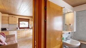 A kitchen with wooden cabinets, a microwave, and a window. - Apartment 'Natale 7' with Mountain View, Balcony and Wi-Fi (Livigno)