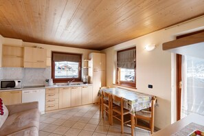 Een kleine keuken met houten kastjes, een eettafel en een raam.
