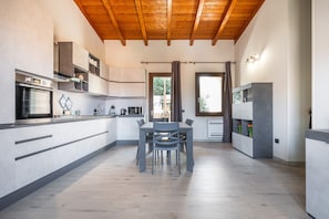 A modern kitchen with wooden beams, a dining area, and a view through a window. - Apartment 'Matilde' with Mountain View, Wi-Fi and Air Conditioning (Villa San Pietro)