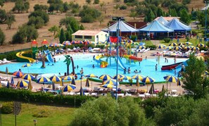 A large outdoor swimming pool with multiple slides and water play areas, surrounded by beach umbrellas and lounge chairs. - Apartment 'Matilde' with Mountain View, Wi-Fi and Air Conditioning (Villa San Pietro)