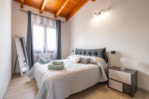 A bedroom with a bed, nightstand, mirror, and curtains. - Apartment 'Matilde' with Mountain View, Wi-Fi and Air Conditioning (Villa San Pietro)