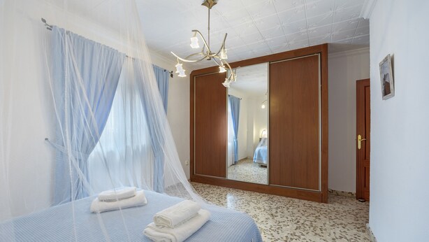A bedroom with a bed, a canopy, a mirror, and a wardrobe.