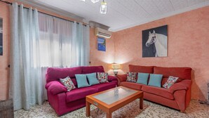 A living room with two sofas, a coffee table, a painting, and an air conditioning unit.