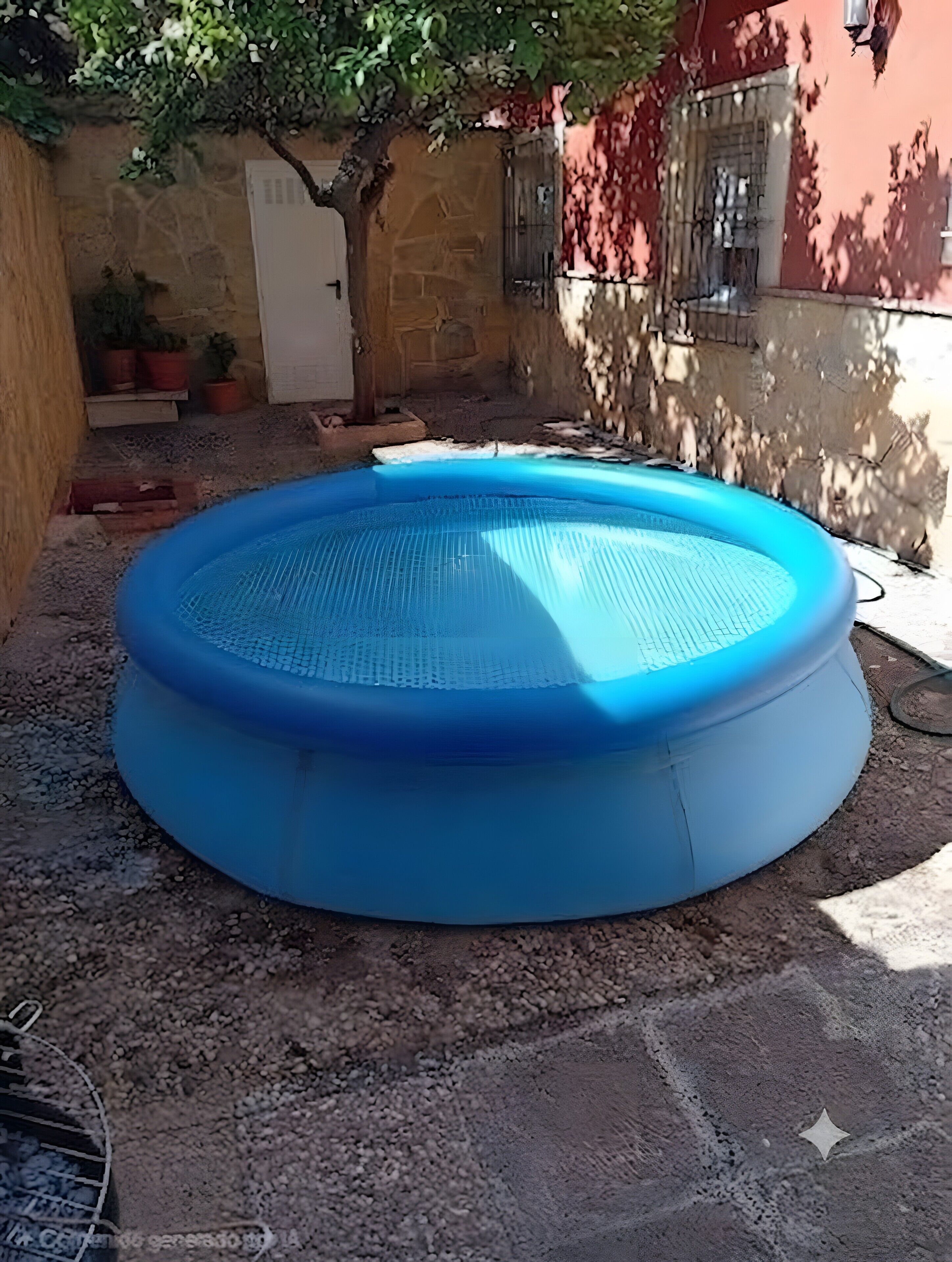 Een rond, blauw opblaasbaar zwembad in een binnentuin met een stenen muur en een boom.