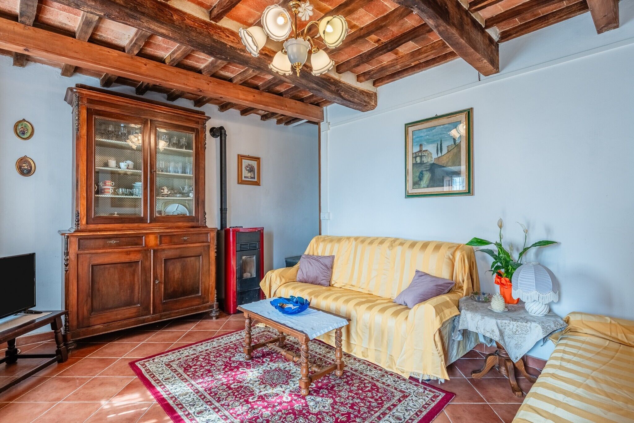 A living room with a wooden cabinet, a sofa, a television, and a red rug.