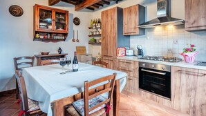 Una cocina con armarios de madera, una mesa de comedor con sillas, una estufa y un reloj en la pared.