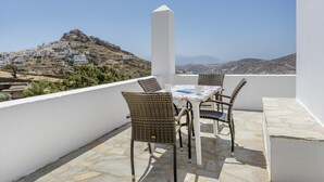 A terrace with wicker chairs and a table, overlooking a hillside village. - Apartment '8' with Sea View, Wi-Fi and Air Conditioning (Ios Chora)