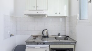 A compact kitchen with white cabinets, a stainless steel sink, a kettle, and a built-in oven. - Apartment '8' with Sea View, Wi-Fi and Air Conditioning (Ios Chora)