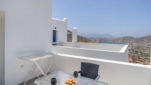 Un balcón con una mesa, dos sillas, un tendedero y vistas a un paisaje montañoso.