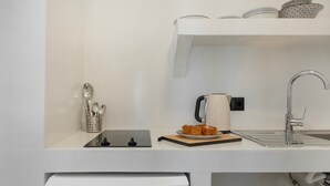 Una cocina moderna con estación de carga para Tesla, una tetera, un plato de comida y un lavabo.
