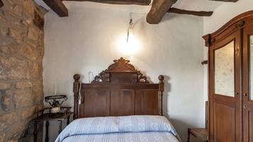 Een slaapkamer met een houten bed, een nachtkastje, een lamp en een kledingkast.