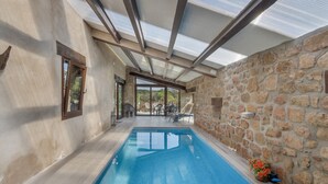 An indoor swimming pool with stone walls and a glass ceiling. - Country House 'Masia Manonelles' with Private Pool, Terrace & Air Conditioning (Unknown)