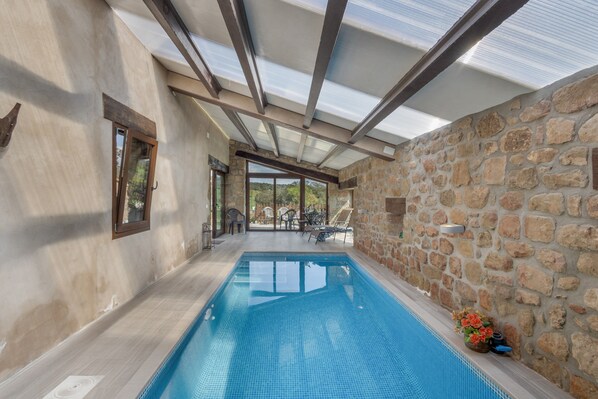 An indoor swimming pool with stone walls and a glass ceiling.