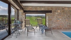 A room with a stone wall, a pool, and a view of the countryside. - Country House 'Masia Manonelles' with Private Pool, Terrace & Air Conditioning (Unknown)