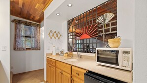 A compact kitchen with wooden cabinets, a microwave, and a sink. - Lovely Couples Suite with Amazing Views and Privacy (Emmett)